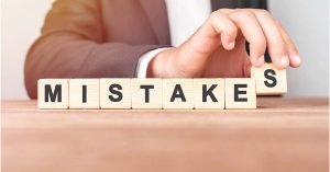 A business owner spells the word "mistakes" using wooden blocks lined up on a table.